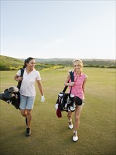 Women carrying golf bags on golf course