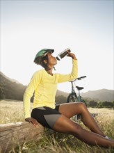 Mixed race biker taking a break and drinking water