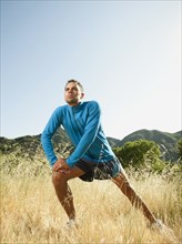 Athletic mixed race man stretching outdoors before exercise