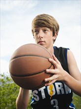 Caucasian teenager playing basketball