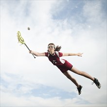 Caucasian teenager in mid-air playing lacrosse