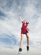 Caucasian teenager in mid-air playing lacrosse