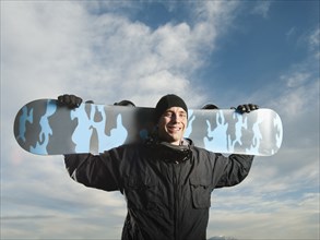 Caucasian man holding snowboard