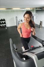 Mixed race woman running on treadmill