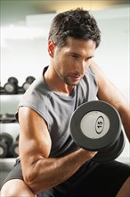 Mixed race man lifting dumbbells in gym