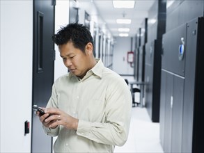 Asian businessman using cell phone in server room
