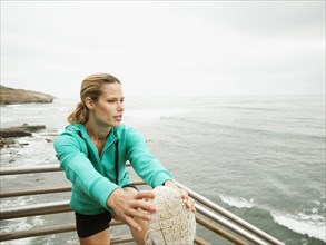 Caucasian woman stretching before exercise next to ocean
