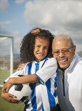 Man smiling with granddaughter on soccer field