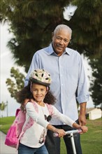 Man standing with granddaughter outdoors