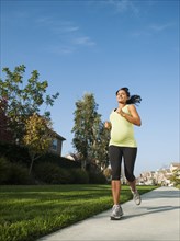 Pregnant Hispanic woman jogging in park