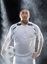 Asian soccer player standing in rain