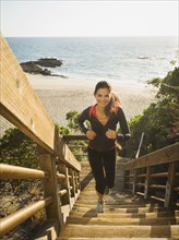 Mixed race woman climbing steps on beach