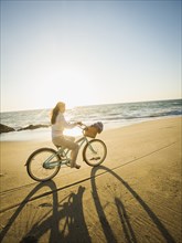 Mixed race woman riding bicycle on beach