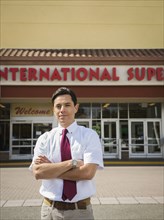 Hispanic businessman standing outside grocery store