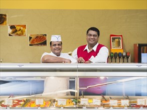 Businessman and chef behind restaurant counter