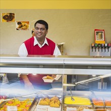 Indian businessman behind restaurant counter