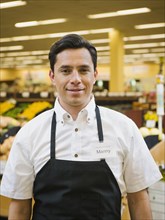 Hispanic worker smiling in grocery store