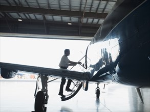 Caucasian pilot boarding airplane in hangar