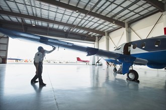 Caucasian pilot examining airplane in hangar
