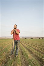 Caucasian farmer with shovel in crop field