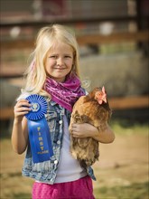 Caucasian girl with prize winning chicken on farm