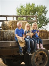 Caucasian children sitting on truck on farm