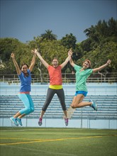 Caucasian women jumping for joy in stadium field