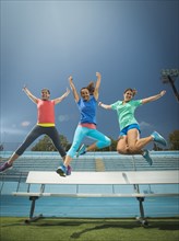 Caucasian women jumping for joy in stadium