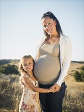 Pregnant mother and daughter in rural field