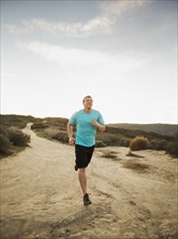 Caucasian man jogging on dirt path