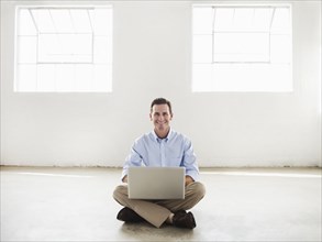 Caucasian businessman using laptop in empty office