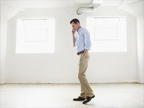 Caucasian businessman talking on cell phone in empty office