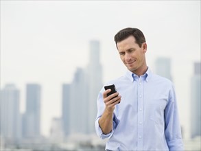 Caucasian businessman using cell phone on urban rooftop