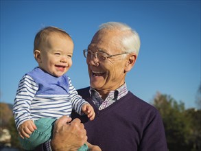 Older man holding grandson outdoors
