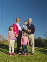 Older couple and grandchildren smiling together outdoors