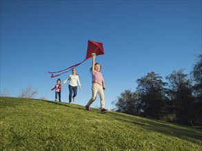 Mother and children flying kite in park