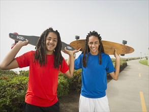 Black teenage boys carrying skateboards on street