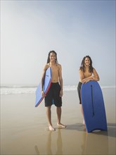 Black teenage boys with boogie boards on beach