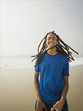 Black teenage boy laughing on beach