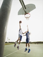 Teenage boys playing basketball on court