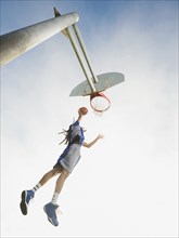Black basketball player dunking ball in hoop