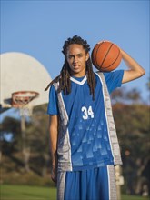 Black teenage boy holding basketball on court