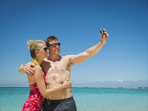 Caucasian couple taking selfie on tropical beach
