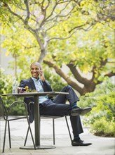 Black businessman working and eating lunch outdoors