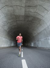 Black man running in urban tunnel