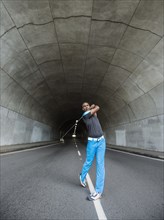 Black man playing golf in urban tunnel
