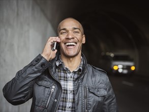 Black man talking on cell phone in urban tunnel