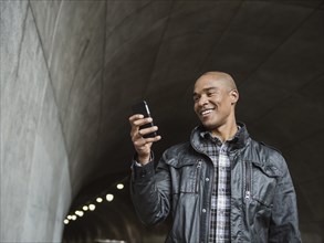 Black man using cell phone in urban tunnel