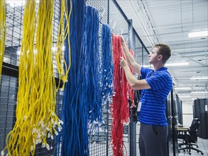 Caucasian technician hanging cables in server room