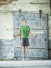 Caucasian man jumping rope in warehouse